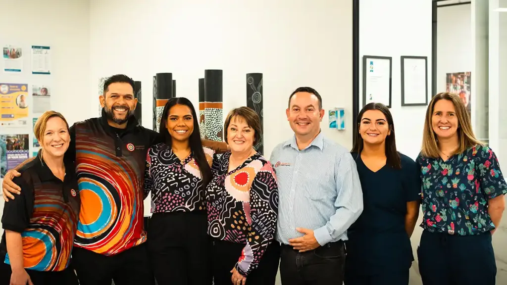 A group of seven smiling professionals posing together in an office